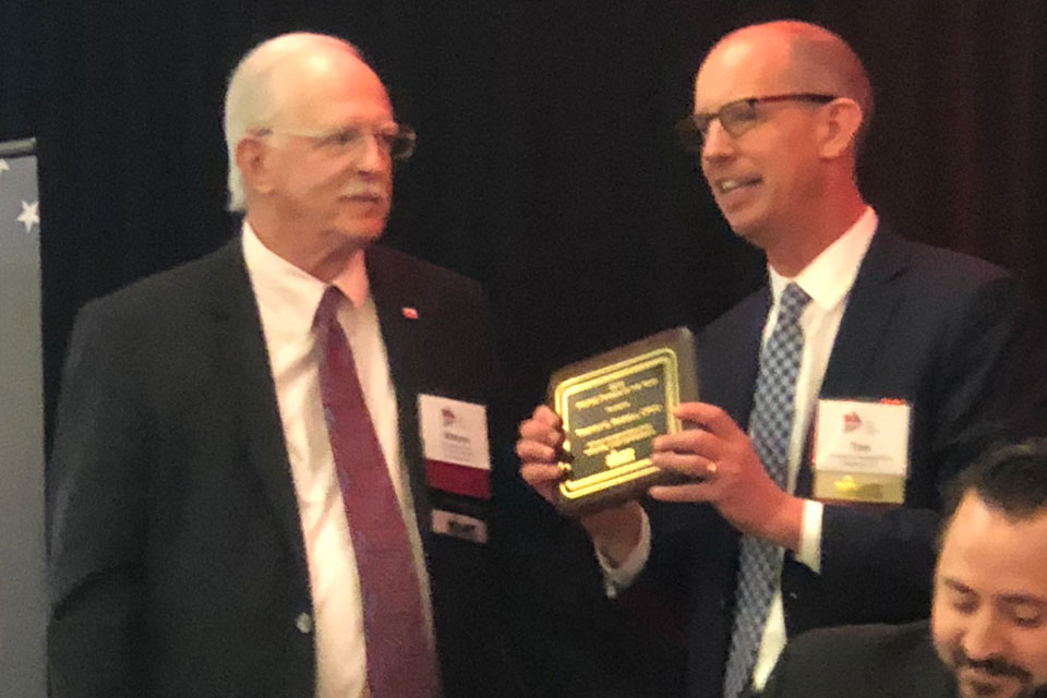 L-R: PIA National Vice President/Treasurer Wayne White presents PIACT National immediate past President and PIACT past President Timothy G. Russell, CPCU, with the PIAPAC Person of the Year award. At table: PIA National Vice President, Government Relations Jon Gentile.